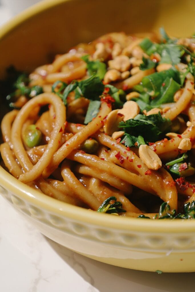 spicy peanut noodles in a large yellow bowl