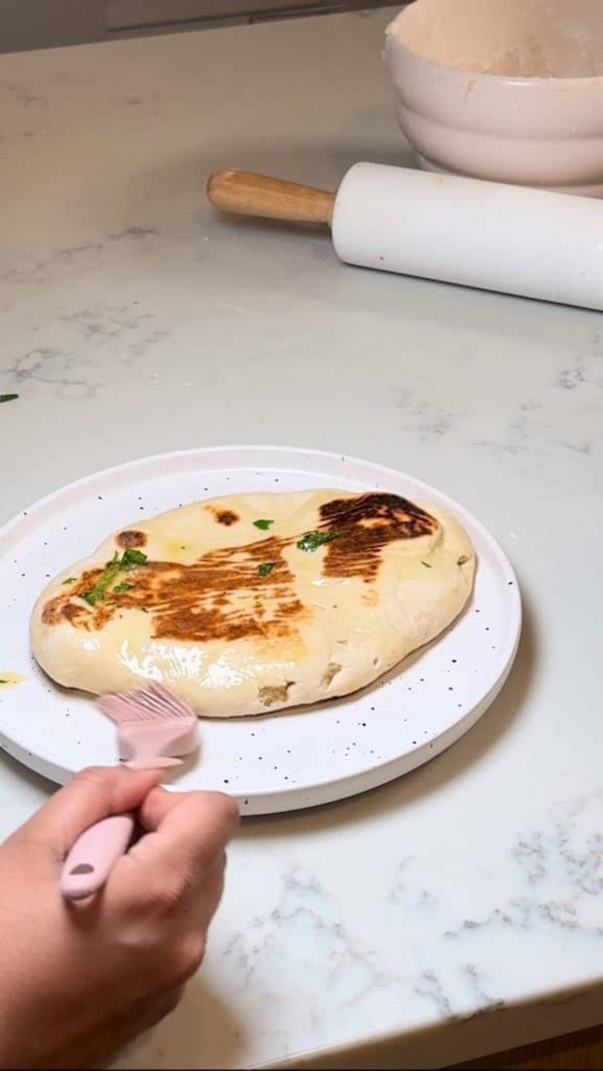cheesy garlic naan being brushed with butter