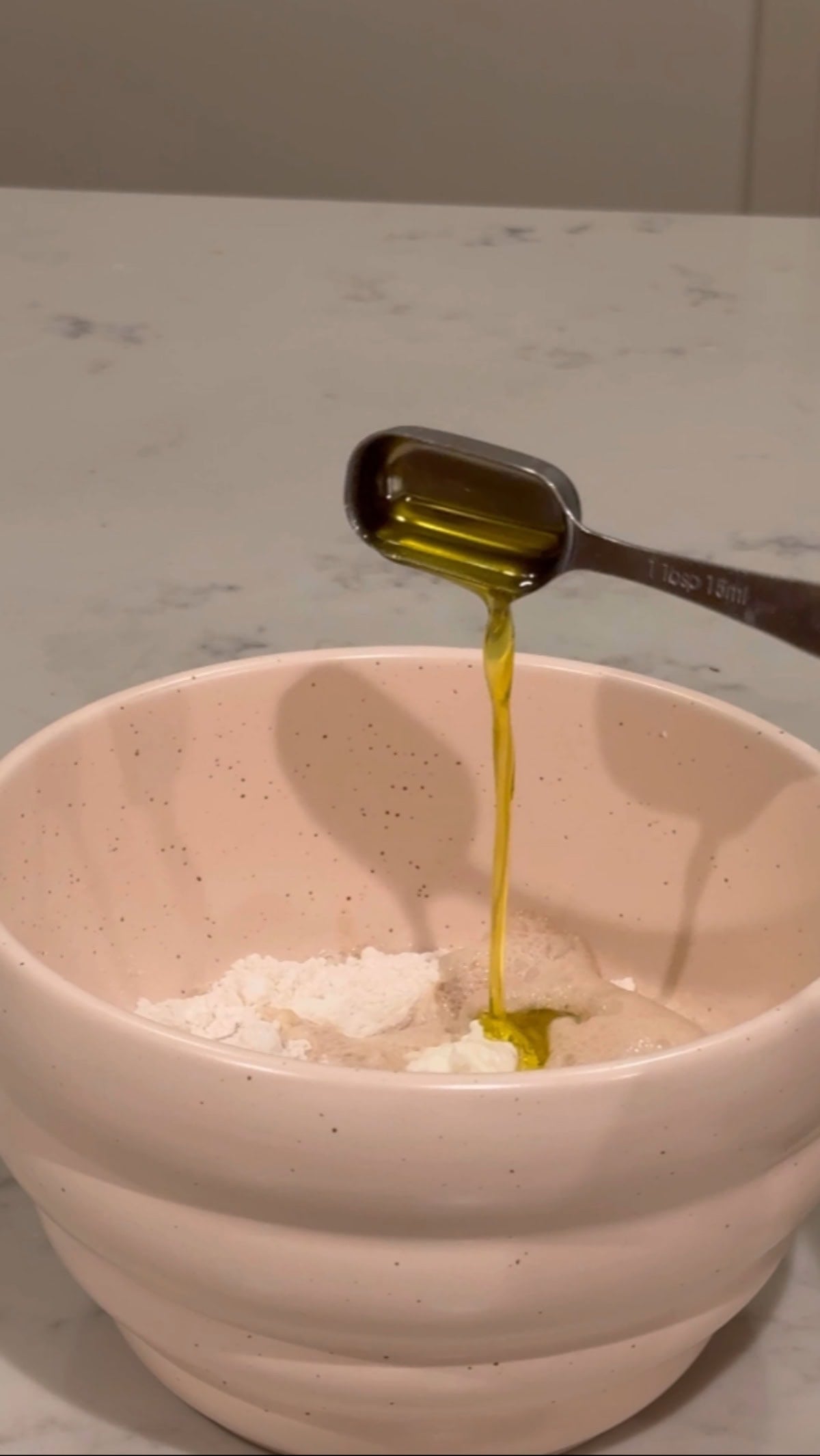 oil being poured into the mixing bowl