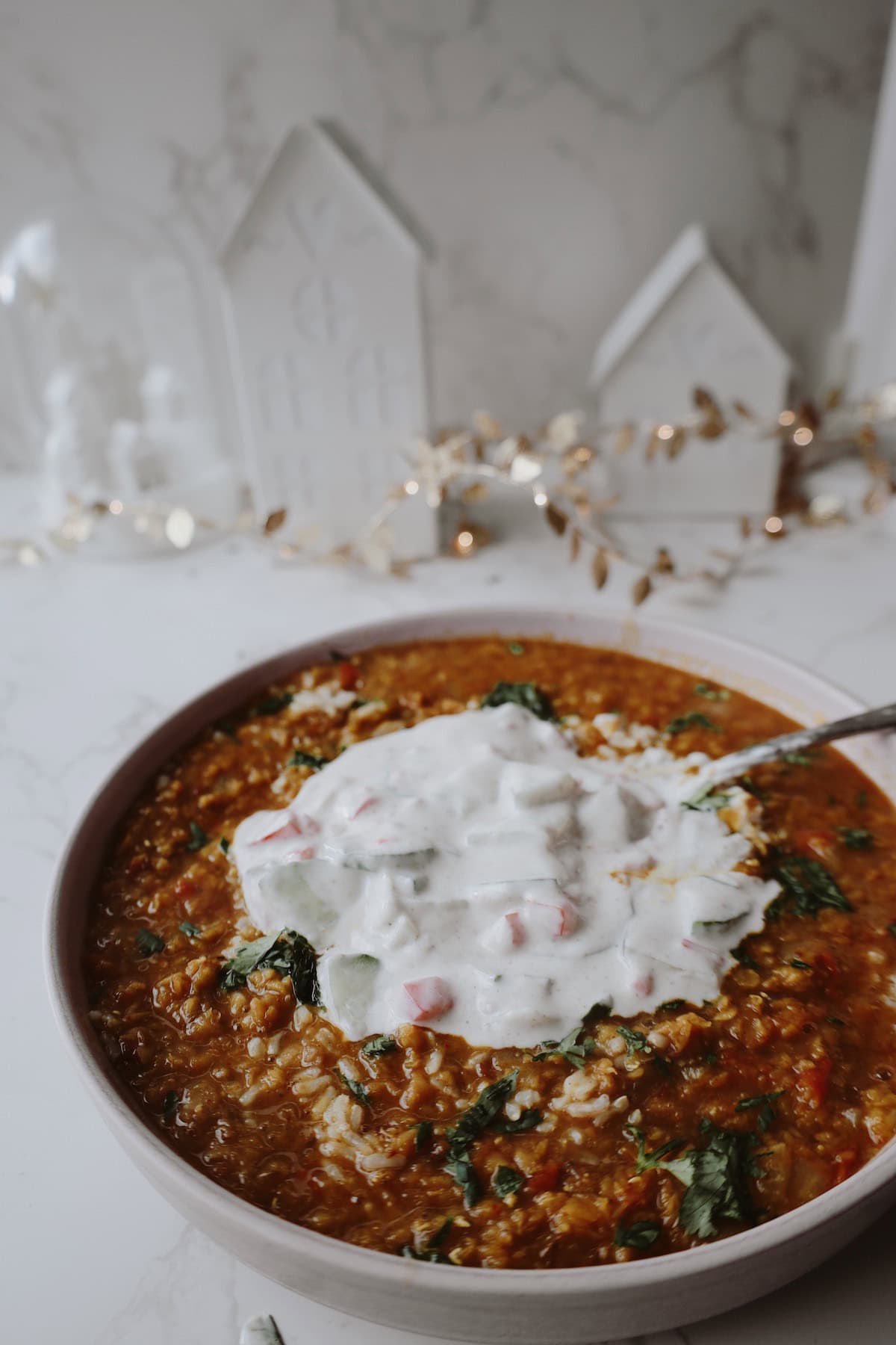 A bowl of lentil soup and rice, topped with lots of yogurt raita.
