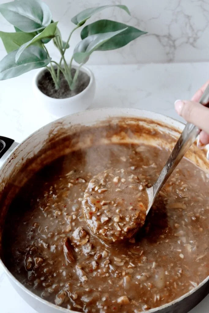 mushroom gravy being scooped by a ladle 