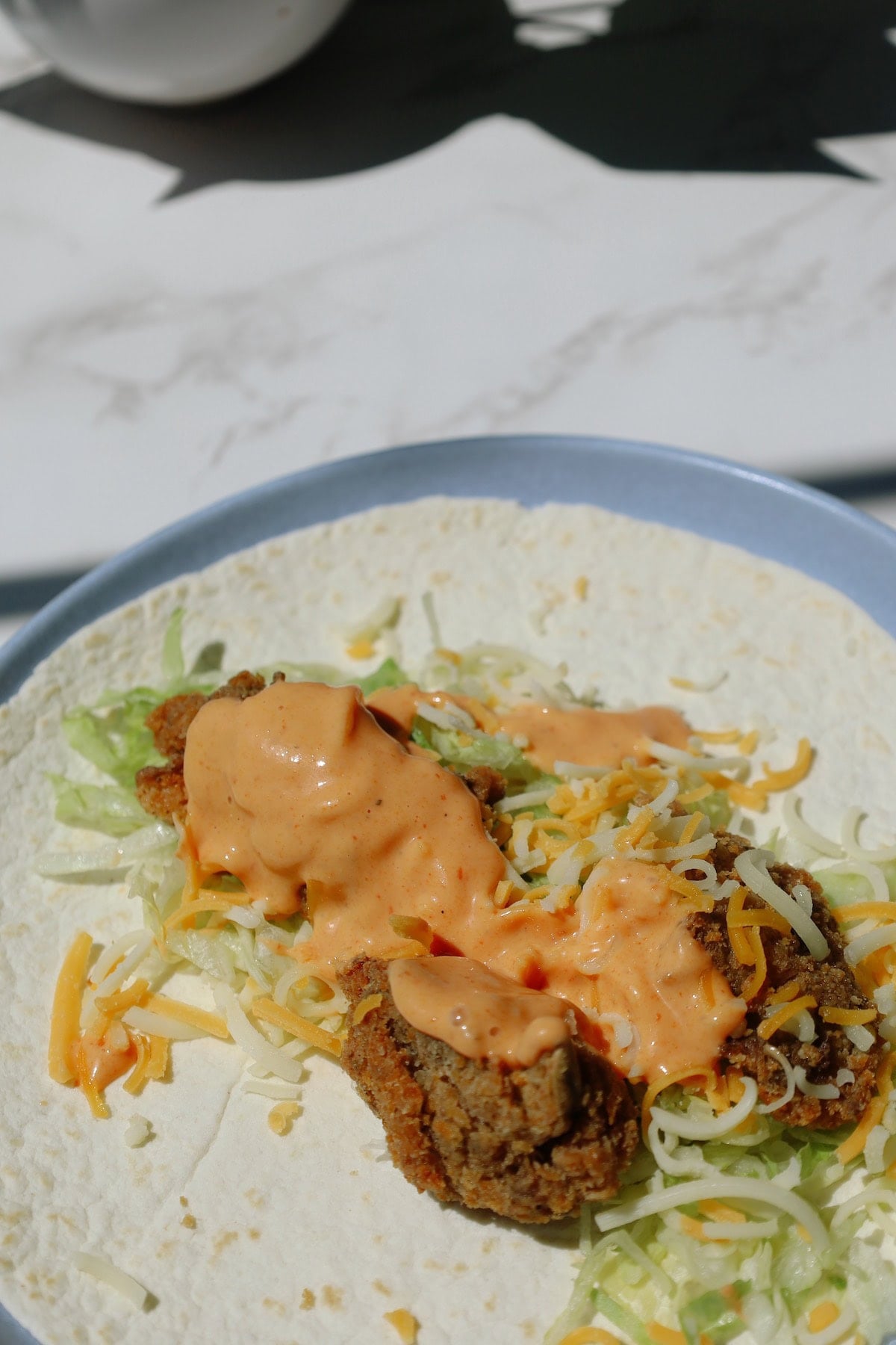 Vegetarian snack wrap with fried oyster mushrooms and spicy sriracha ranch inside a flour tortilla.