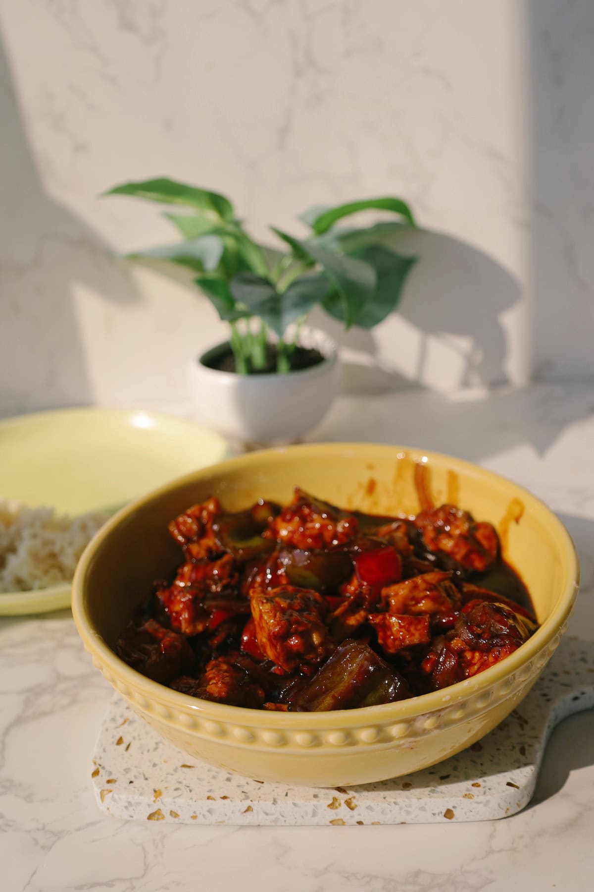 Bowl of sweet and sour tofu with red and green bell peppers coated in a tangy sauce.