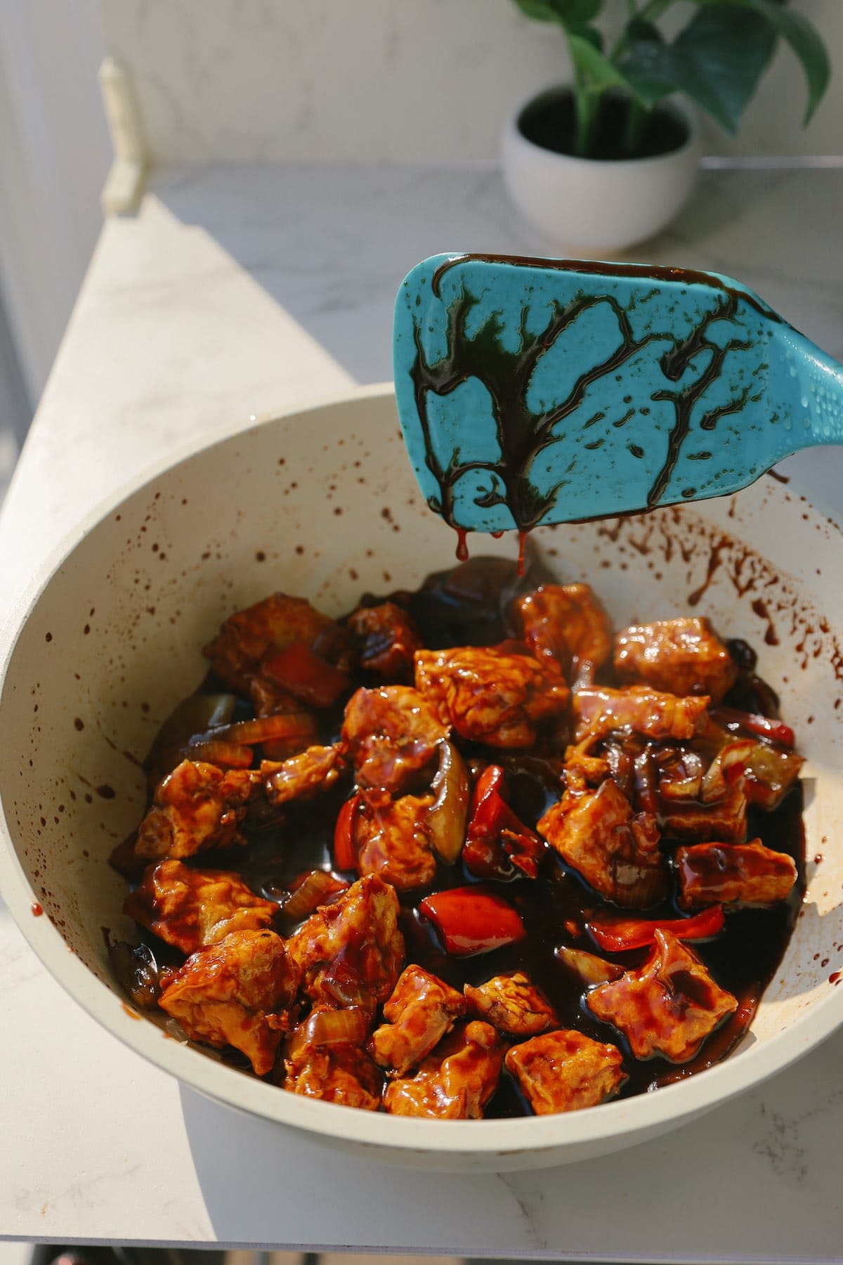 Crispy tofu and colorful bell peppers coated in glossy sweet and sour sauce in a skillet.