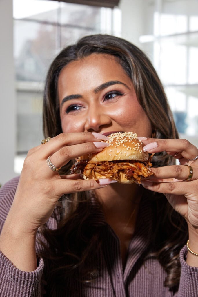 Shreya Walia holding a burger and smiling.