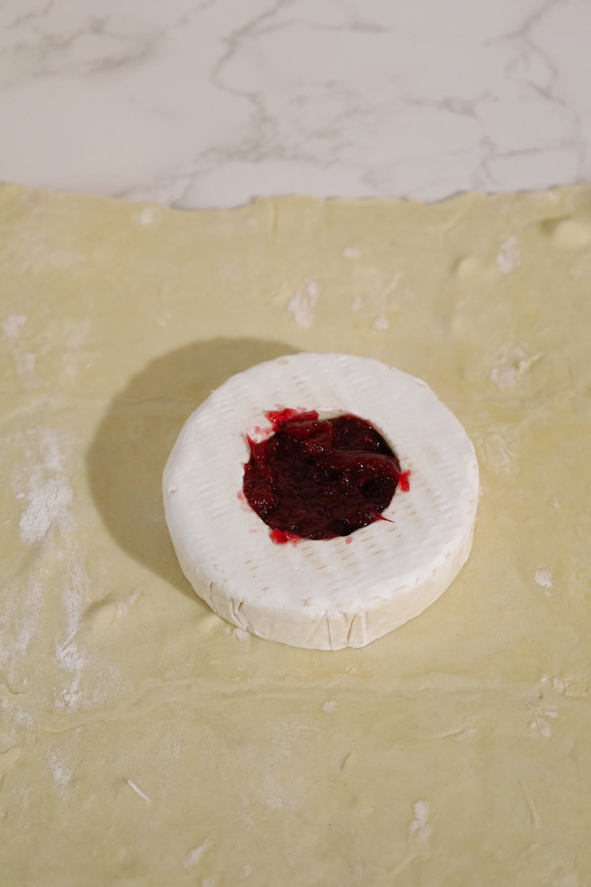 Cranberry sauce fills the center of a brie wheel resting on puff pastry.