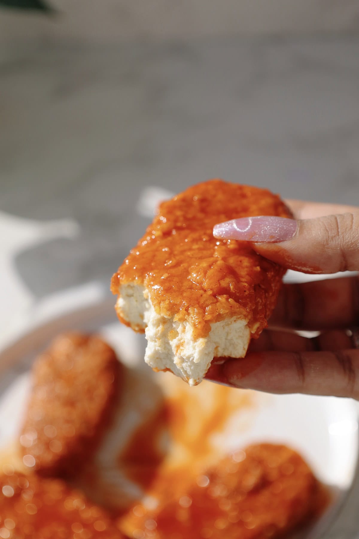 The tender is being held in someone's hand with a bite taken out of it.