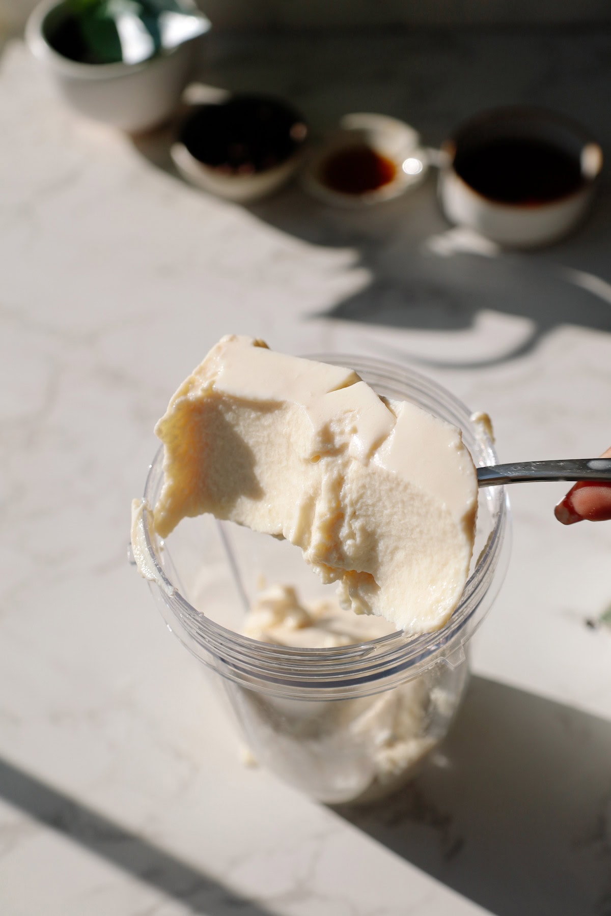 silken tofu being scooped into a blender for the chocolate pudding