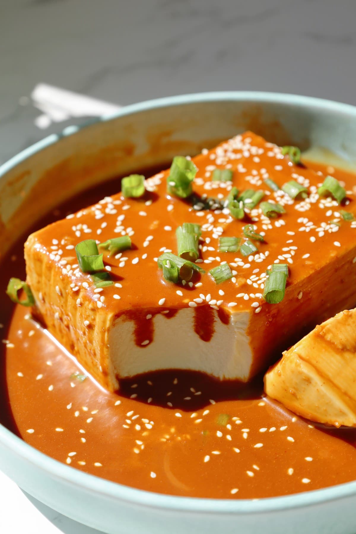 Step five: garnish the tofu with scallions and sesame seeds before serving.