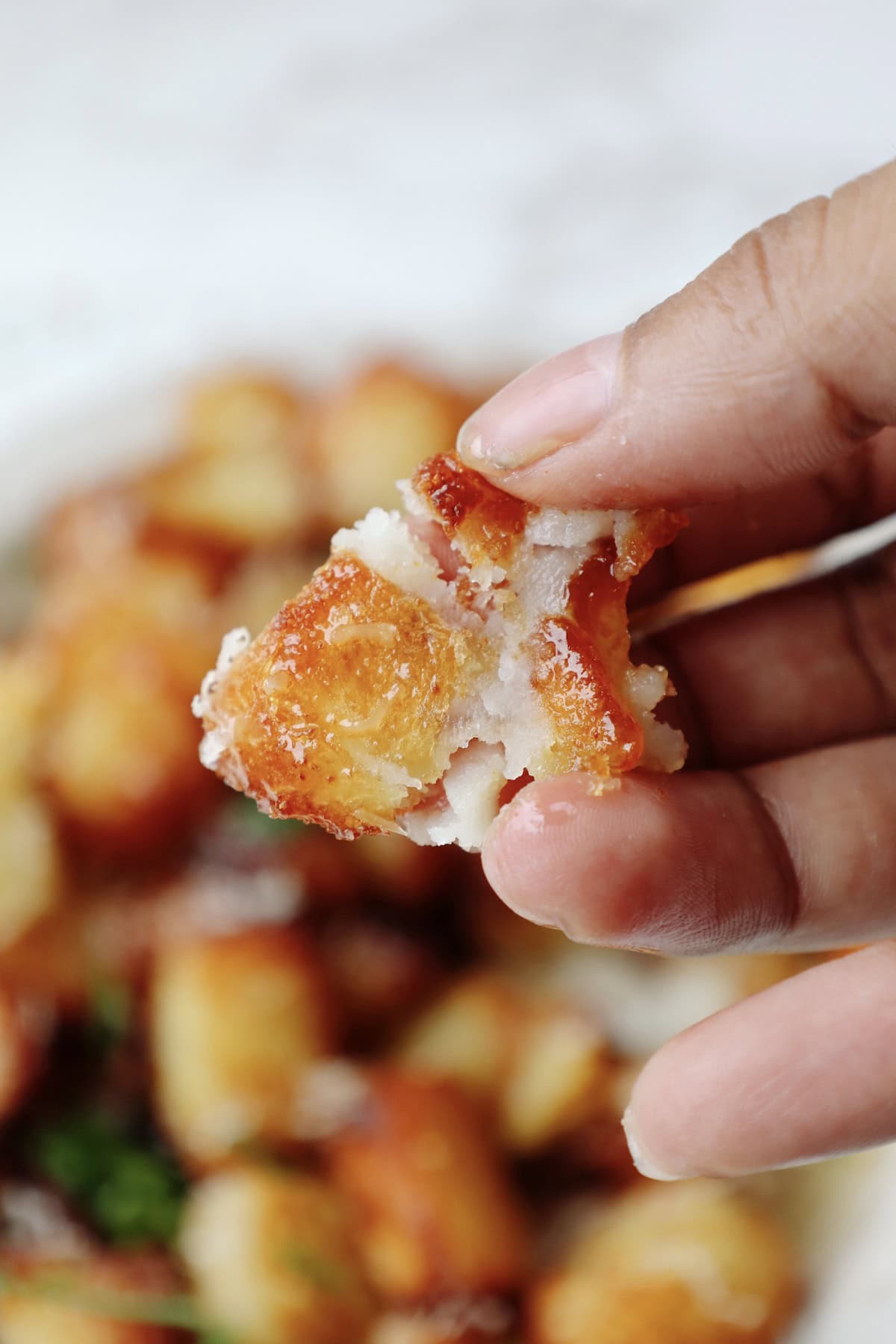 A crispy potato smashed between someone's fingers.