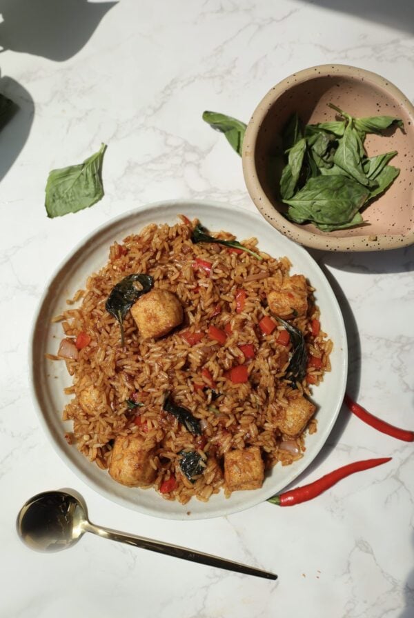 Thai basil fried rice on a plate with a spoon next to it.