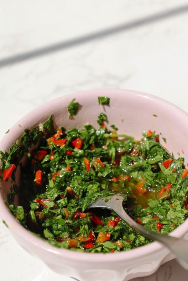 My chimichurri sauce recipe in a bowl with a spoon.