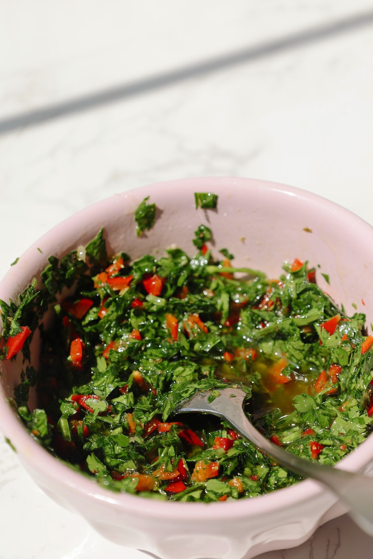 My chimichurri sauce recipe in a bowl with a spoon.