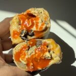 Hand holding a freezer breakfast burrito with hot sauce.
