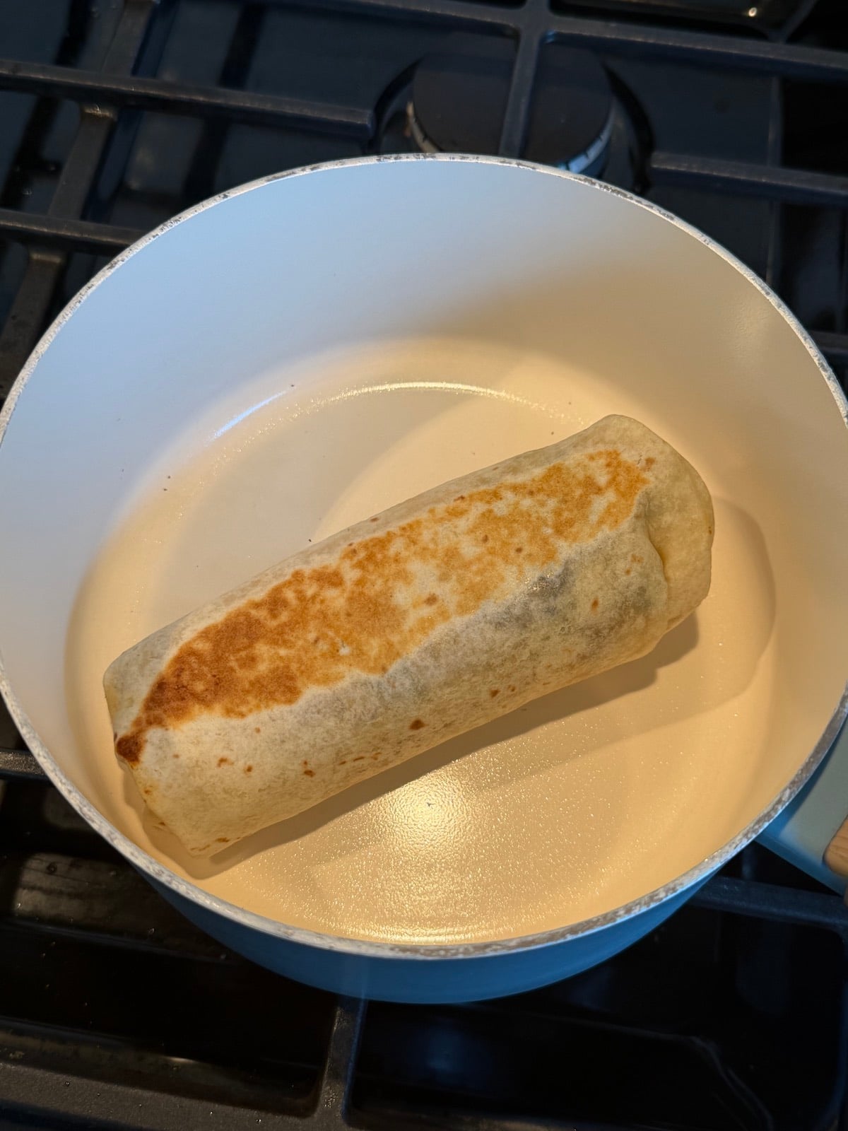 Reheating the breakfast burrito in a skillet.