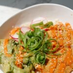Tofu katsu bowl with sesame seeds and cucumbers.