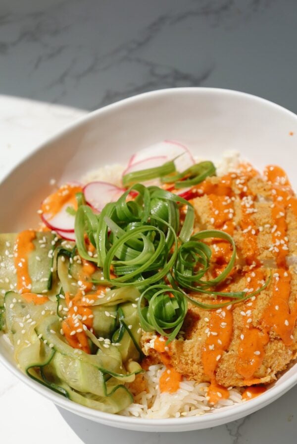 Tofu katsu bowl with sesame seeds and cucumbers.