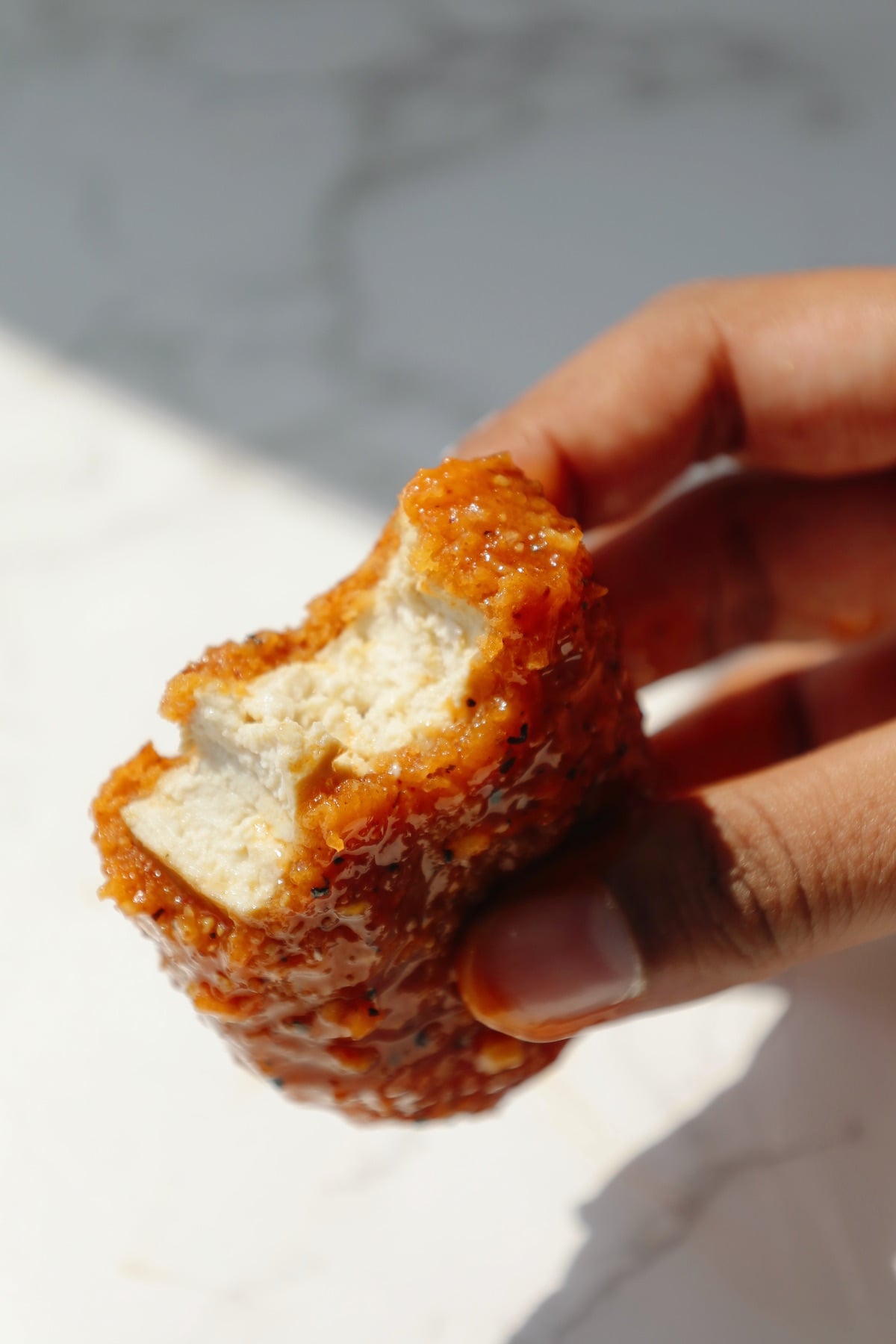 Lemon pepper vegan chicken tenders with a bite taken out.