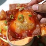 Crab rangoon nachos with sweet chili sauce on top.