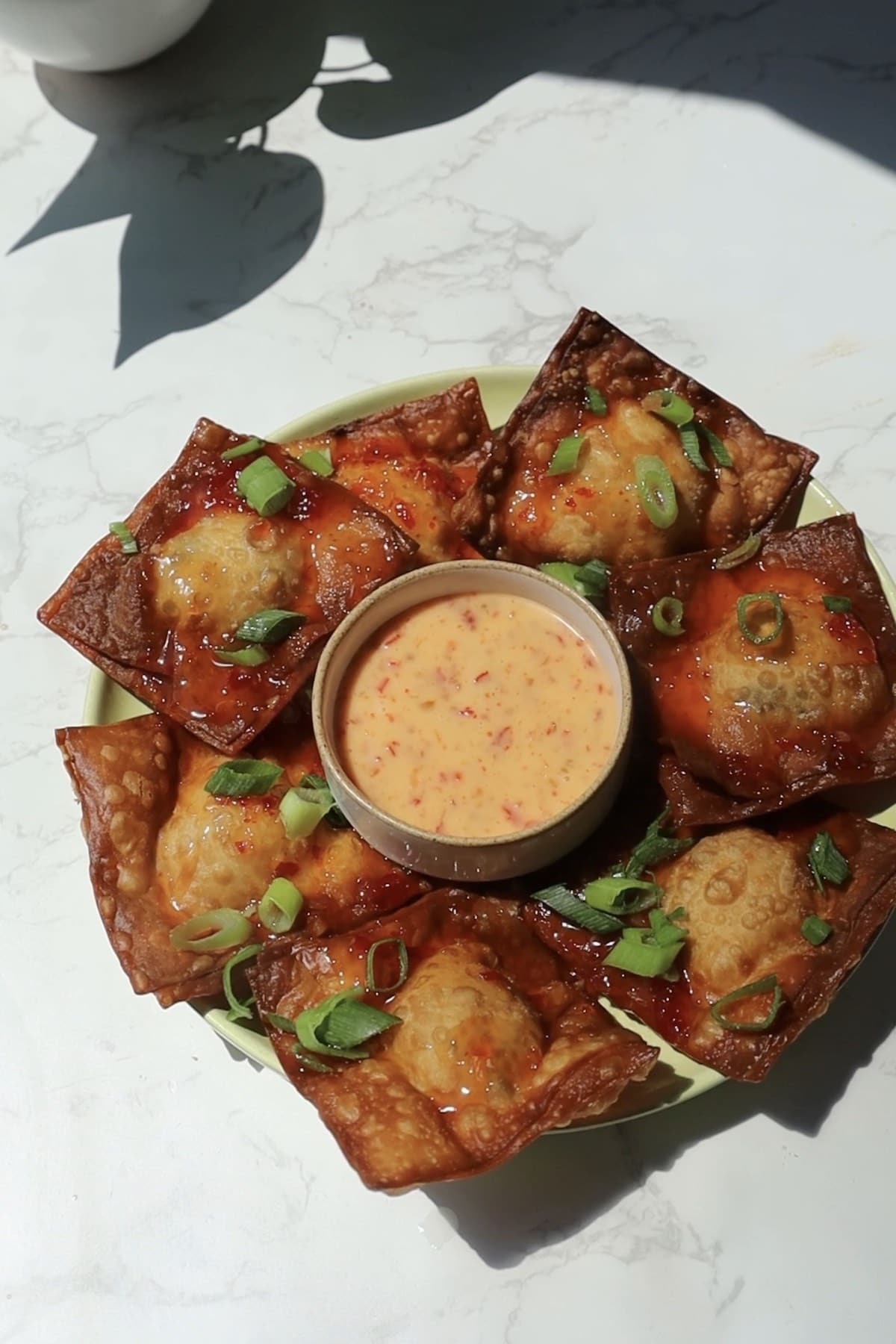 Crab rangoon nachos on a plate with scallions.