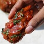 Thai sweet chili wing held in someone's hand.