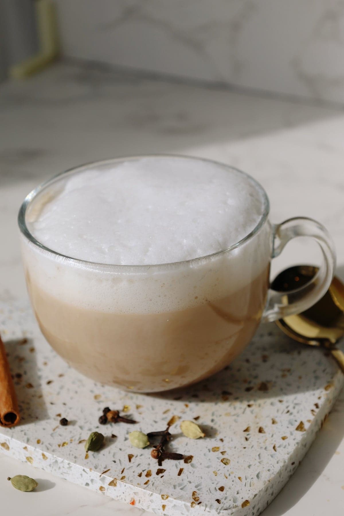 Chai latte recipe in a clear mug with extra foam.