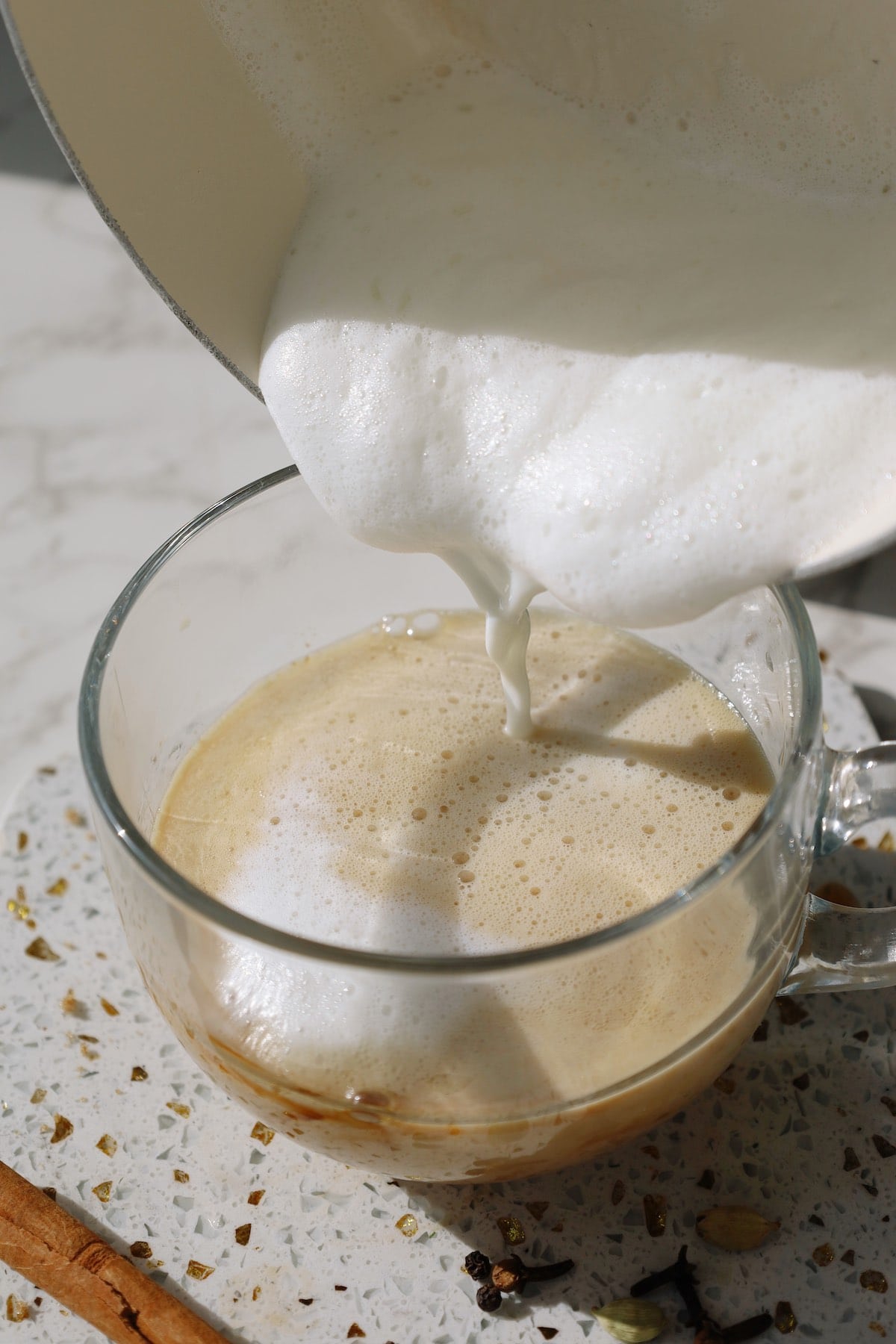Pouring frothed milk into the chai concentrate for a latte.