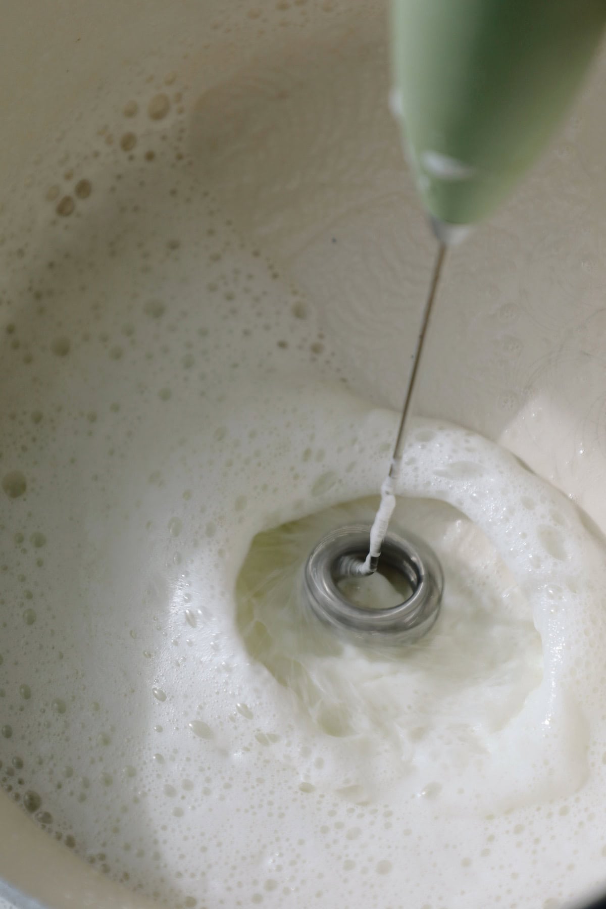 Froth milk in a small saucepan with a frother.