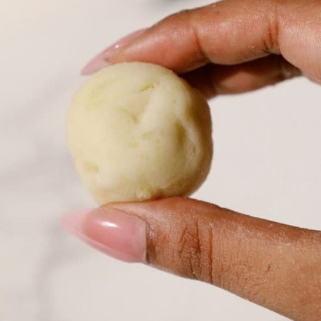 a hand holding a single mashed potato ball.