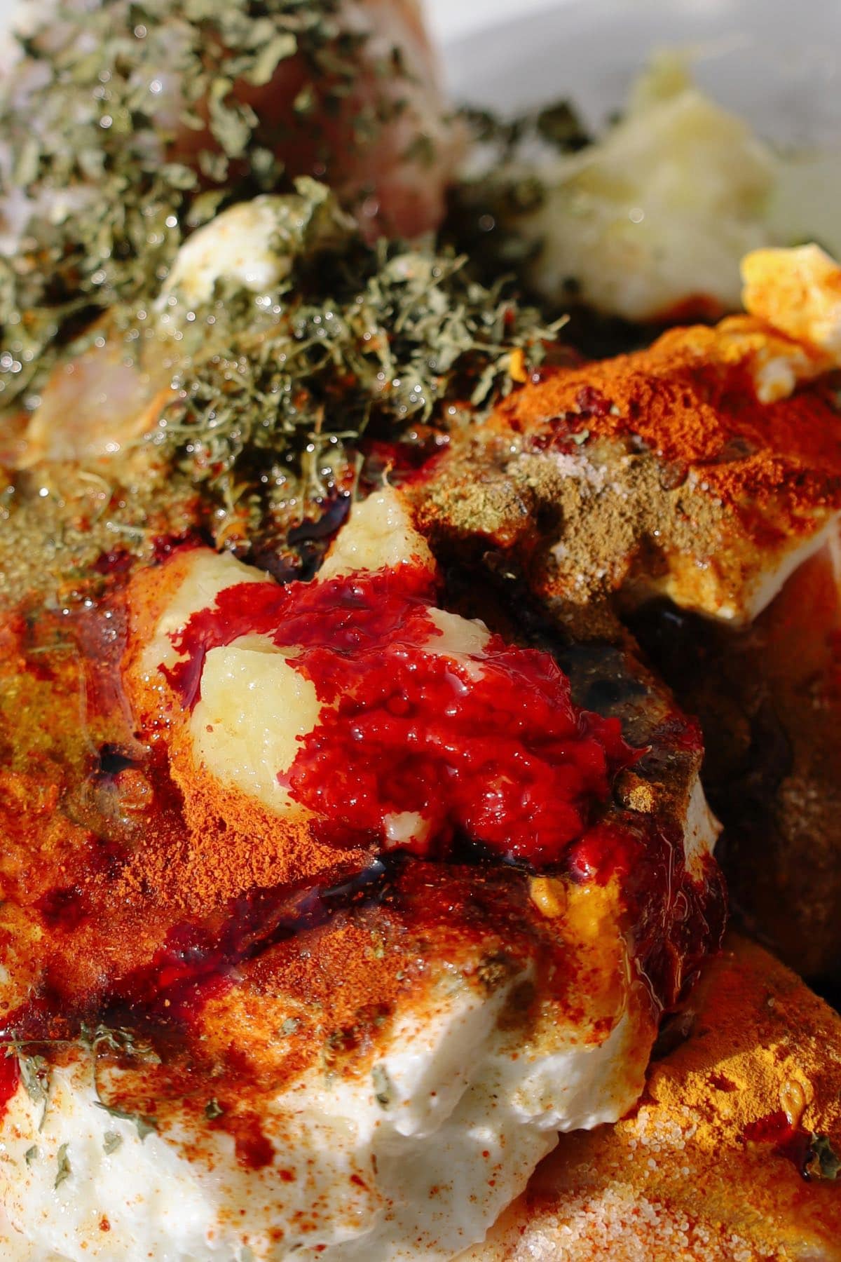 Mixing yogurt, Kashmiri chili powder, kasuri methi, and spices for the marinade.