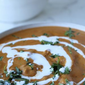 A bowl of butter "chicken" made with soya chaap, topped with fresh cream and cilantro.